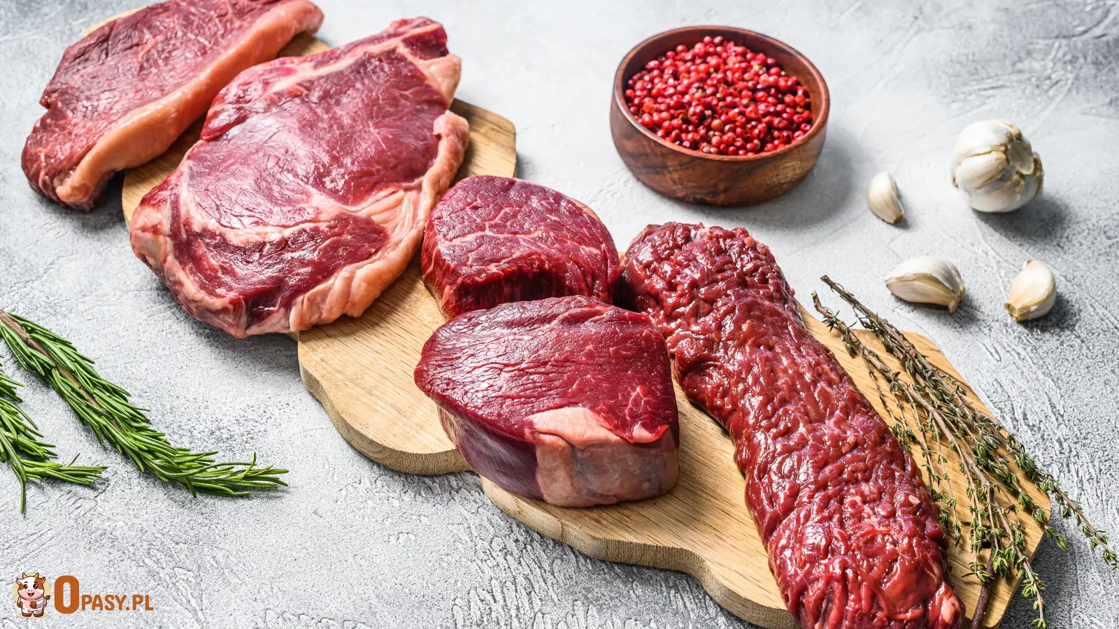 wieże surowe steki wołowe różnego rodzaju, w tym polędwica, rostbef oraz antrykot, na drewnianej desce, z dodatkiem ziół, czosnku i przypraw, prezentujące wysoką jakość